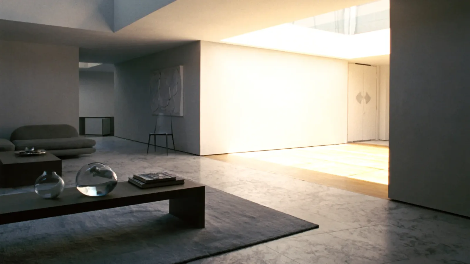 A finished villa living room in daylight: stone floor, plastered walls, low walnut table and a linen sofa
